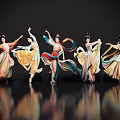 Women dancing in colorful traditional costumes with flowing skirts against black background on reflective floor