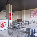 Modern Restaurant Interior with Red Signage White Tables Chairs Gray Walls and Staircase