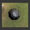 Conical Stone Tower Standing In Green Grass Field With Small Door And Windows