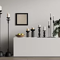 Black Candle Holders With White Candles On Console Table With Fruit Bowl And Monstera Plant