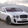 White Luxury Sports Car With Black Wheels Front Grille And Mountain Sky Background