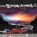 Modern Exhibition Booth With Colorful Hanging Light Decorations Red Car Display Tables Chairs And Green Plants