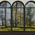 Black Framed Arched Floor To Ceiling Windows Reveal Trees Grass And Side Potted Plants