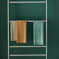 Beige Orange And Light Green Towels Hanging On Metal Rack Against Green Wall