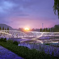 Illuminated Arc Shaped Bridge Over Water at Sunset Surrounded by Greenery Trees and People Walking