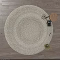 Round White Woven Rug on Wooden Floor with Decorative Items and Small Plant