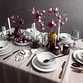 Elegant Dinnerware Set with White Plates Bowls Metal Utensils Wine Glasses and Floral Vase Decor