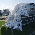 Modern Office Building with Irregular Glass Curtain Wall Design Surrounded by Lawn and Greenery