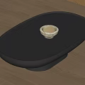 Modern Oval Coffee Table With Dark Smooth Surface And White Bowl On Wooden Floor