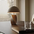 Table Lamp With Wooden Base Fabric Shade On Dark Table With Book Glass And Stone