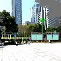 Entrance Gate Featuring Red Sign in Plaza with Modern High Rise Buildings and Green Trees