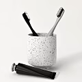 Stylish Bathroom Accessories Set With White Speckled Cup Black Gray Toothbrushes And Black Toothpaste Tube