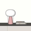 Modern White Spherical Table Lamp With Pink Base Metal Stand And Books On Light Background