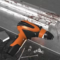 Orange And Black Electric Drill With Metal Parts Screws And Nuts On Workbench