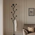 Black Tree Shaped Coat Rack With White Bathrobe Near Brown Sofa And Geometric Pillow