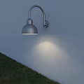 Curved Arm Silver Wall Lamp Dome Shade On White Wall Casts Warm Light Over Grass