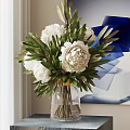 White Peonies and Green Leaves in Transparent Vase on Table with Blue Abstract Painting