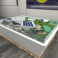 Sand Table Model In Glass Covered Display Case With Building Structures And Yellow Logo Screen