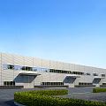 Modern Industrial Factory Exterior With Metal Wall Large Windows Landscaped Bushes And Blue Sky Background