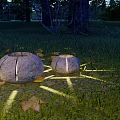 Round Stone Outdoor Lights Glowing On Garden Lawn With Autumn Leaves And Light Projection