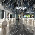 Elegant Banquet Hall Interior With White Chairs Table Settings Floral Decorations And Reflective Floor