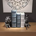 Decorative Books in Blue Silver with Zebra Figurines and Wall Art on Wooden Surface