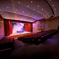 Cultural Center Auditorium Interior With Red Seats Stage Blue Screen Red Curtains And Ceiling Lights