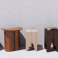Various Wooden Stools With Curved Tops And Different Leg Designs Against Minimalist Gray Background