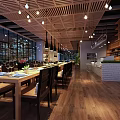 Modern Restaurant Interior Featuring Long Tables Black Chairs Wooden Floors Pendant Lights And Open Kitchen