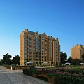 Brown Exterior Residential Building With Lush Greenery Garden Pathway Benches And Clear Blue Sky