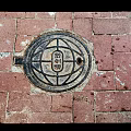 Traditional Manhole Cover On Red Brick Pavement With Intricate Circular Design