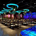 Modern Restaurant Interior With Blue Purple Lighting Circular Hanging Lights Large Screen And Dining Tables