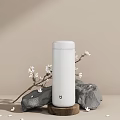 Minimalist White Thermos with White Flower Branches and Stones on Beige Surface