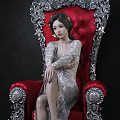 Elegant Woman In Silver Dress Sitting On Red Ornate Chair With Carved Silver Details