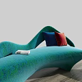 Teal Curved Sofa with Red and Blue Pillows and Matching Ottoman on Wooden Floor