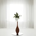 Round Transparent Dining Table With Brown Drop Base White Pot Green Plants White Curtains Bright Window