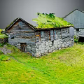 Traditional Wooden House With Grass Roof Stone Walls And Adjacent Building In Green Field