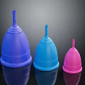 Three Different Colored Menstrual Cups Arranged In A Row On Dark Background