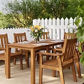 Wooden Dining Chairs With Dining Table Yellow Flowers And White Picket Fence In Garden
