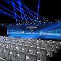 Modern Conference Hall Setup With White Chairs Stage Screen And Blue Lighting