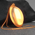 Decorative Jewelry Ornament Set With Gold Oval Shiny Pendant On Black Stone Background
