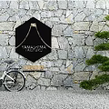 Courtyard Garden Featuring Stone Wall Black Hexagonal Sign White Bicycle Green Pine Tree Gravel Ground