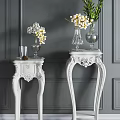 White Carved Side Tables With Glass Vases And Flowers On Gray Wall Backdrop
