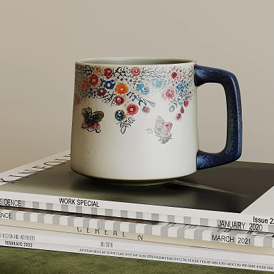 Ceramic Mug with Colorful Floral Patterns Butterflies and Blue Handle Placed On Stacked Magazines 3d model