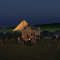 Outdoor Table Under Tent With People Sitting On Grass And Lights At Night