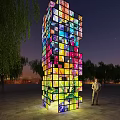 Colorful Illuminated Tower Installation With Trees And Person Standing At Night