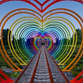 Rainbow Colored Heart Shaped Pergola with Central Pathway Green Trees and Grassy Area