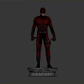 Red Superhero Statue Standing On Square Base With Red Costume And Daggers