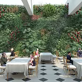 Greenery Filled Restaurant Interior With Living Plant Wall Red Flowers And Dining Tables
