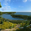 Scenic Landscape of Blue Sky White Clouds Calm Water Green Islands Lush Grassland Winding Path